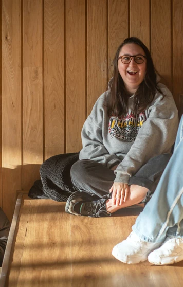 Students relaxing and chatting on wooden tiered seating at the Springburn campus, enjoying the natural light Students relaxing and chatting on wooden tiered seating at the Springburn campus, enjoying the natural light